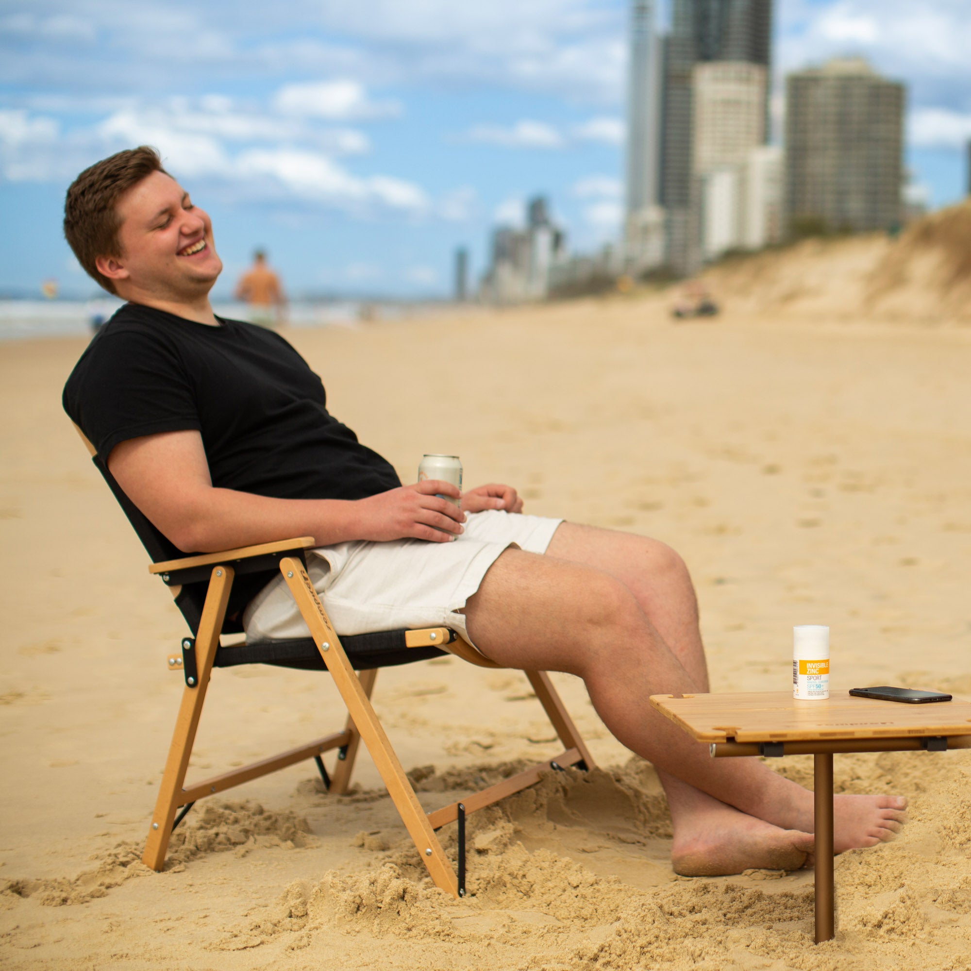 Man relaxing on a beach chair with a cityscape in the background